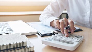 Foto: Hand am Taschenrechner